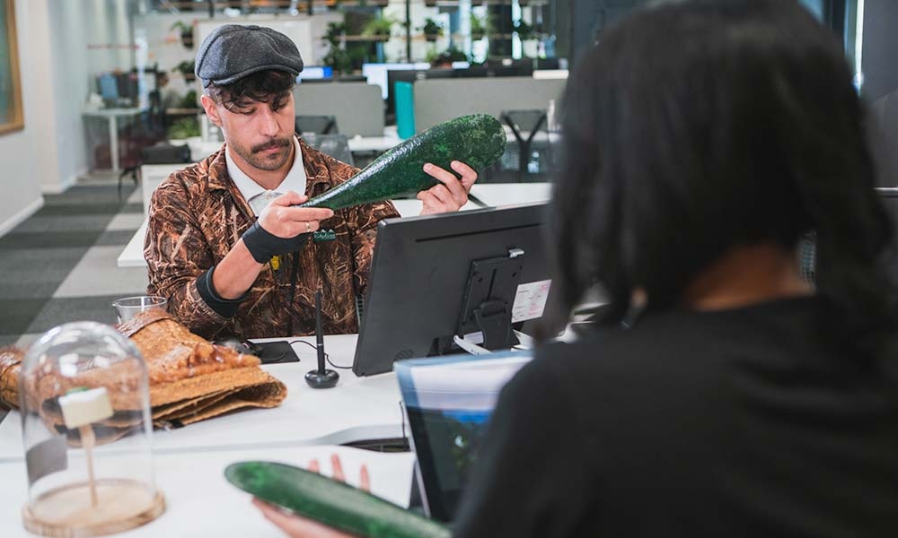 Man wearing a hat looking at a Maori patu greenstone