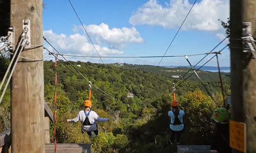 two people riding a EcoZip zipliner a tourism adventure in Auckland