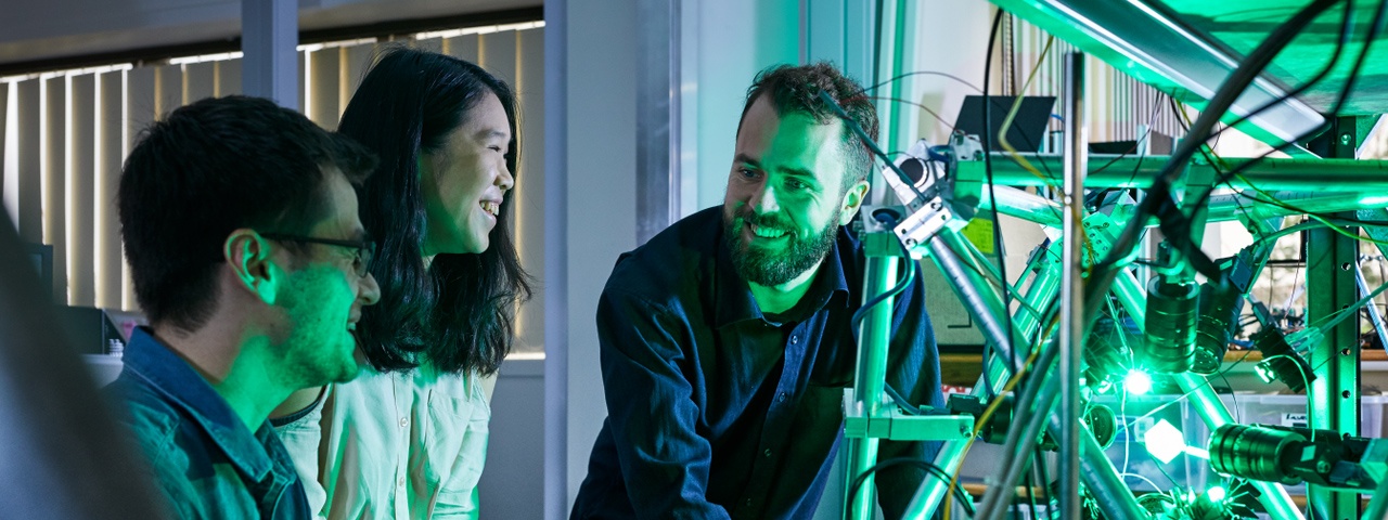 3 people playing with a robotic arm