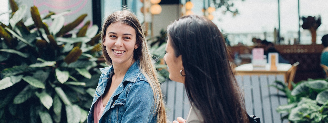 Two girls walking and talking to each other outside