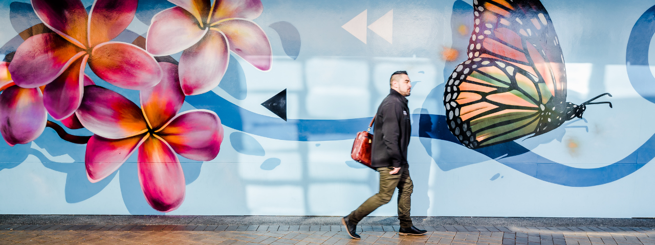 Man walking past Rerenga mural, Manukau