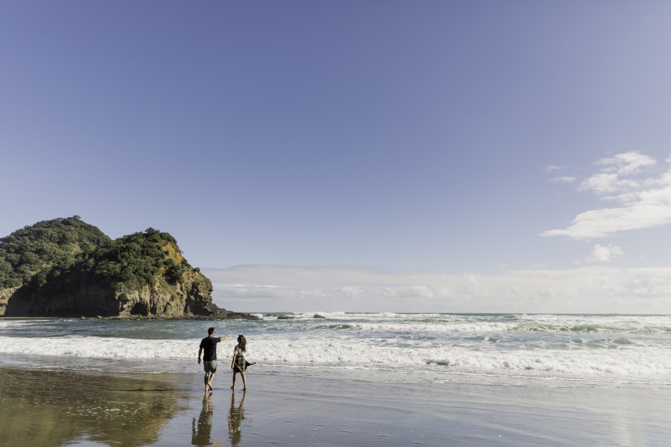 Two people walking on black sand surf beach