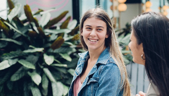 Two girls walking and talking to each other outside