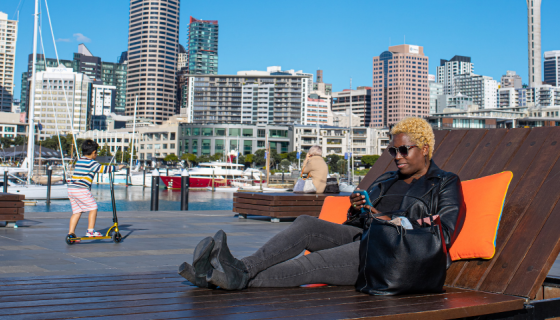 Woman sitting on the large wooden sun loungers at Wynard Quarter