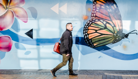 Man walking past Rerenga mural, Manukau