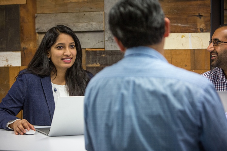 three colleagues discussing work around a table